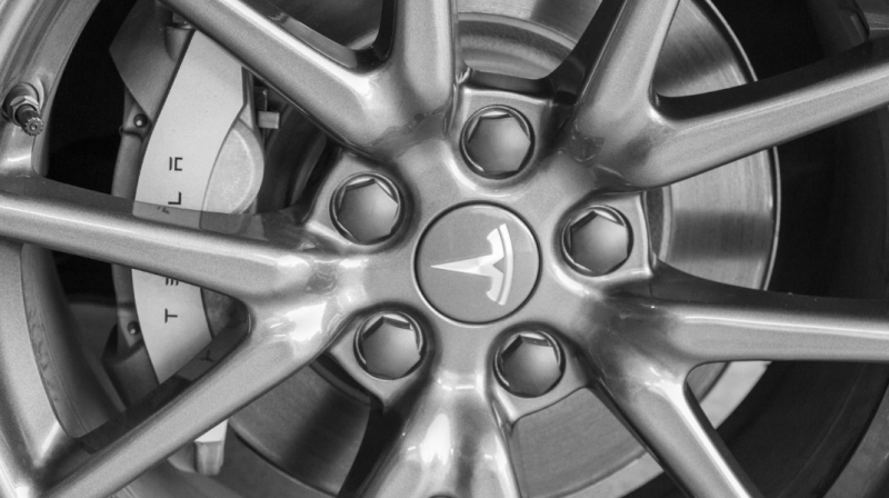 Tesla 特斯拉灰色鋁圈與煞車卡鉗近照，展現精緻的輪轂工藝與品牌標誌